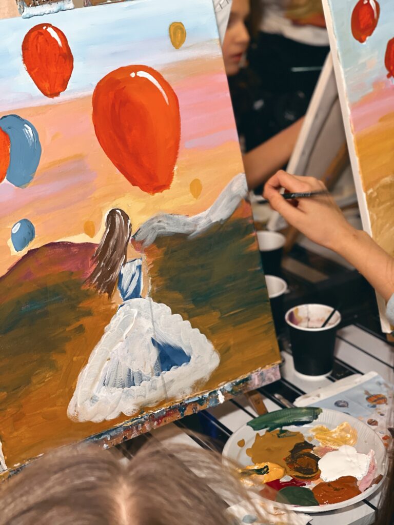 Imagen de un cuadro de una niña con vestido blanco que mira el globo rojo