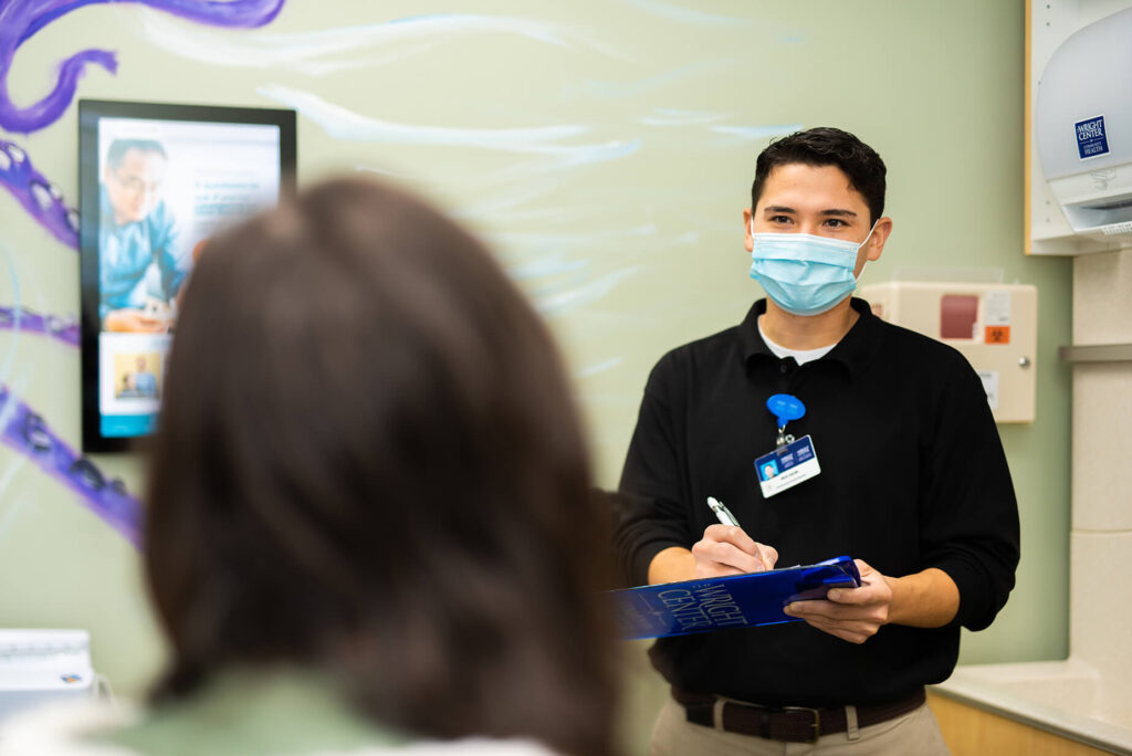 Nick Sardo, a community health worker at The Wright Center for Community 皇家华人 Mid Valley Practice, takes notes while talking to a patient during a recent visit.