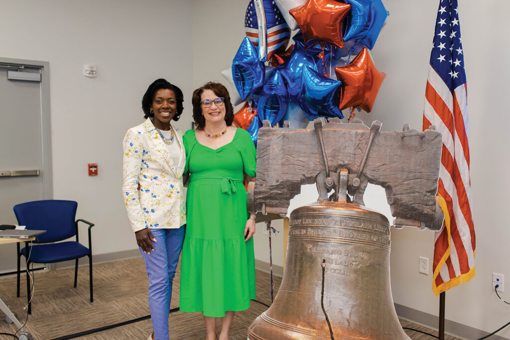 Dr. Thomas and board member standing in front of liberty bell cutout